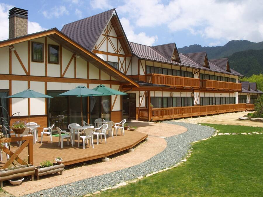 A traditional building with a wooden deck, outdoor seating, and a gravel path.
