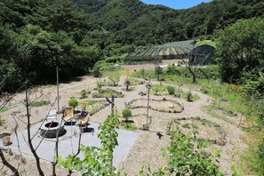 A garden with a stone fire pit, seating area, and a path leading to a green-roofed building. - Bandibyeol Pension (Hongcheon)