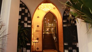 Ein Rundbogen-Eingang mit einer Rezeption, einer Treppe und einer Kristallleuchter.