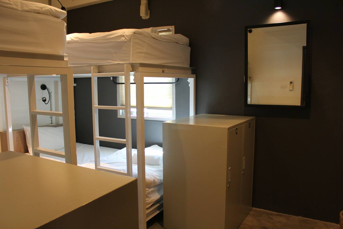 A bunk bed room with a desk and a cabinet.