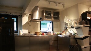 A modern kitchen with stainless steel appliances, a built-in oven, and a window overlooking the street. - Jam Hostel Bangkok (Bangkok)