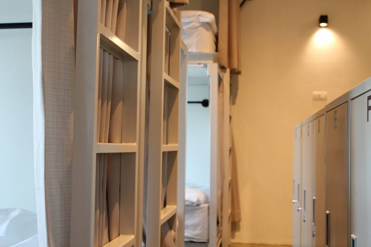 A narrow hallway with a bunk bed, a wardrobe, and a light fixture on the wall.