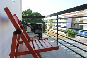 Un balcón con una silla roja y una mesita, con vista a un canal y edificios.