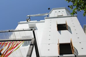 Un edificio alto y blanco con techo plano y numerosas ventanas.