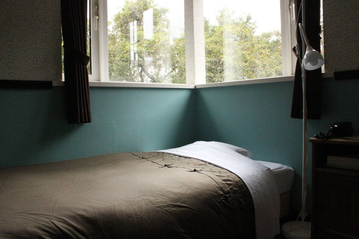 Un dormitorio con una cama, una ventana y una mesita de noche.