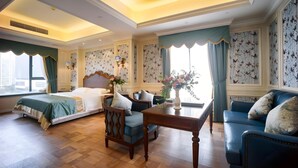 A hotel room with a bed, a sofa, a table, and a chair. There are windows with curtains, a wall with butterfly wallpaper, and a ceiling with recessed lighting. - Chengdu Creyad Hotel (Chengdu)