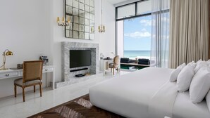 Une chambre d’hôtel moderne dotée d’un grand lit, d’une télévision, d’un bureau et offrant une vue sur l’océan.