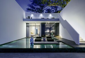 Relax by the pool in a spacious outdoor area with comfortable seating and a well-lit interior space.