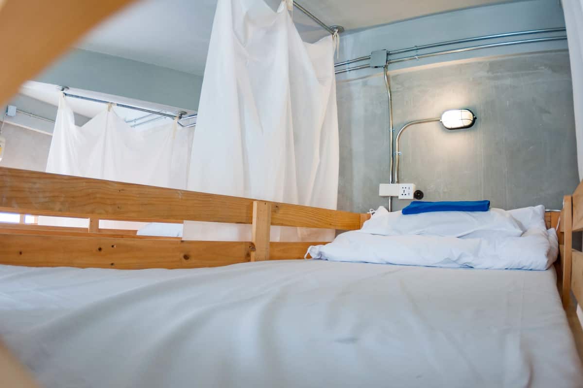 Ein Einzelbett mit Holz-Kopfstück, weißer Bettwäsche und einem weißen Baldachin.