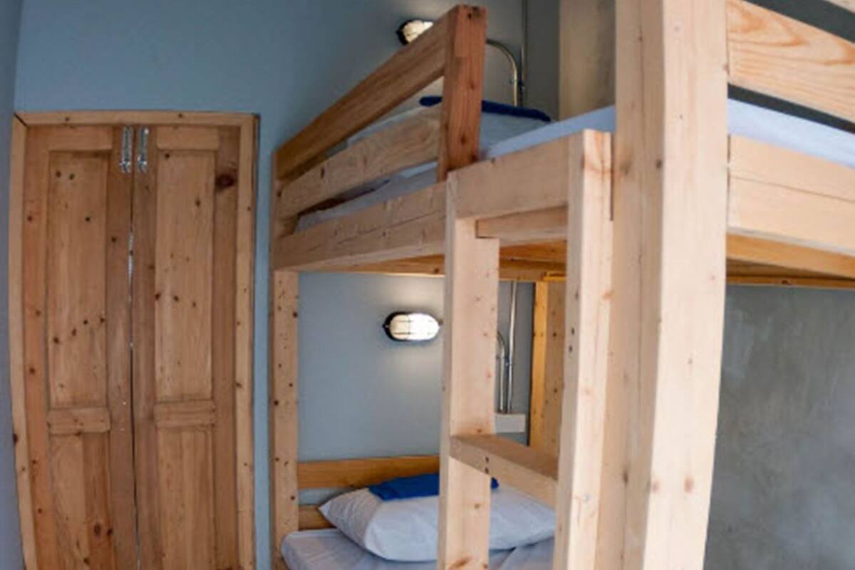 Ein Schlafraum mit Etagenbett, Holzschrank und kleinem Fenster.
