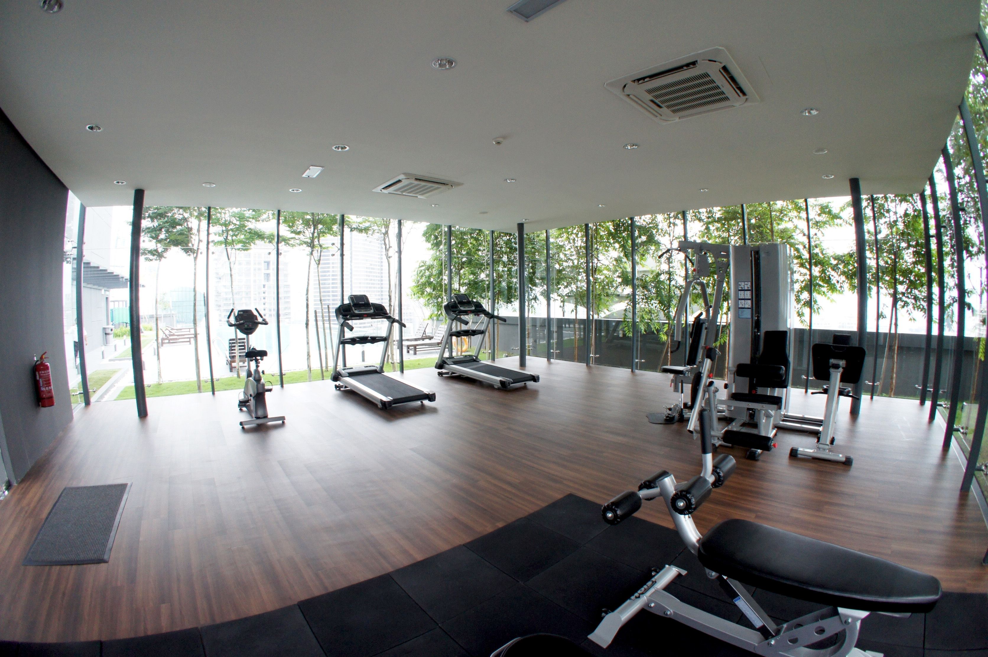 Una palestra moderna con tapis roulant, macchinari per pesi e un'ampia vetrata con vista sulla città.