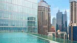 A modern building with a glass facade and a swimming pool in front. - Dorsett Residences Bukit Bintang by De Space (Kuala Lumpur)