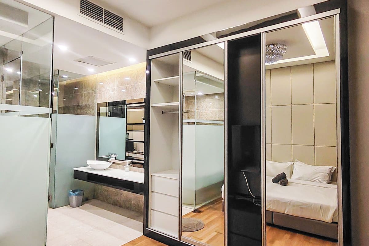 A modern bedroom with a large mirror, a bed, and a walk-in closet.