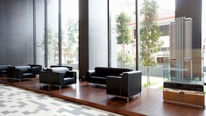 A modern lobby with black sofas, a wooden floor, and large windows overlooking a building and trees. - Dorsett Residences Bukit Bintang by De Space (Kuala Lumpur)