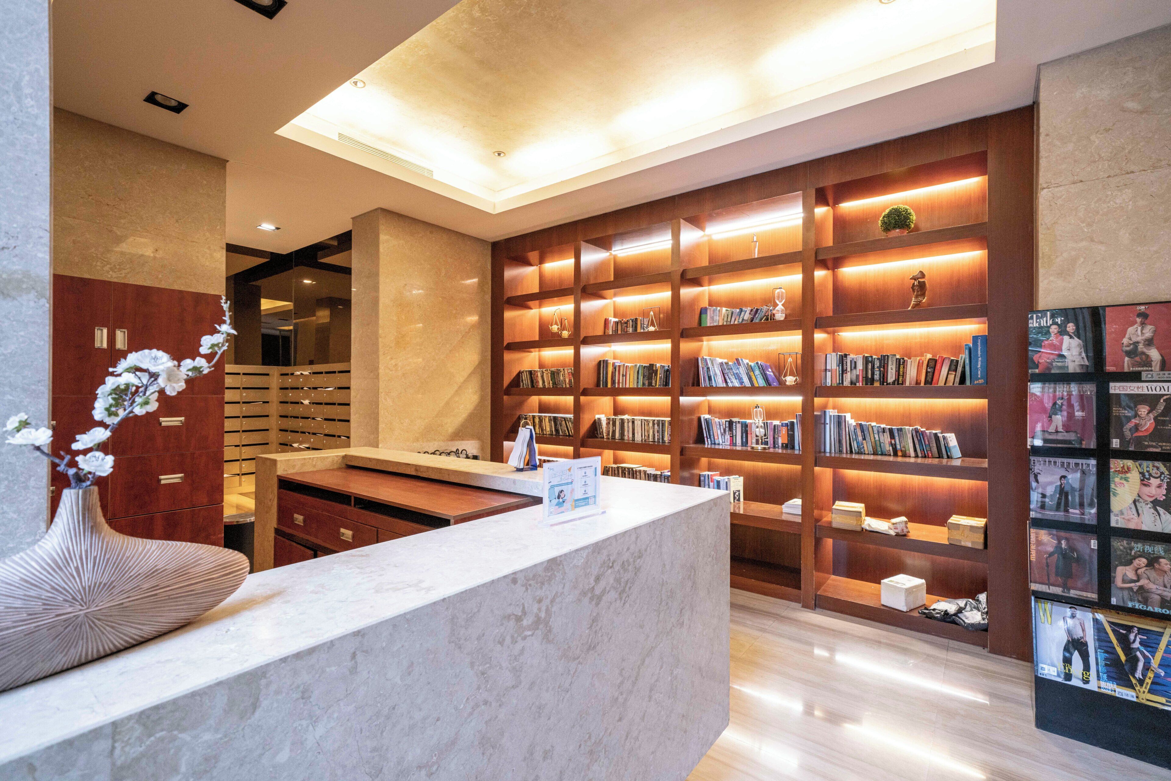 Eine moderne Bibliothek mit Marmor-Empfangsbereich, Holzbögen und einer großen Auswahl an Büchern und Zeitschriften.