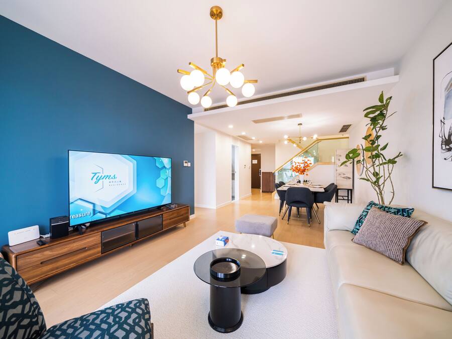 Un saló modern amb televisió plana, un sofà, una taula baixa i una zona de dinar al fons.