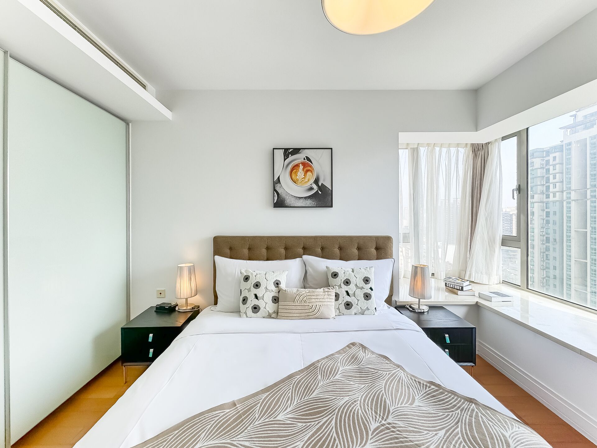 Une chambre moderne avec un grand lit, une vue sur la ville et un tableau accroché au mur.