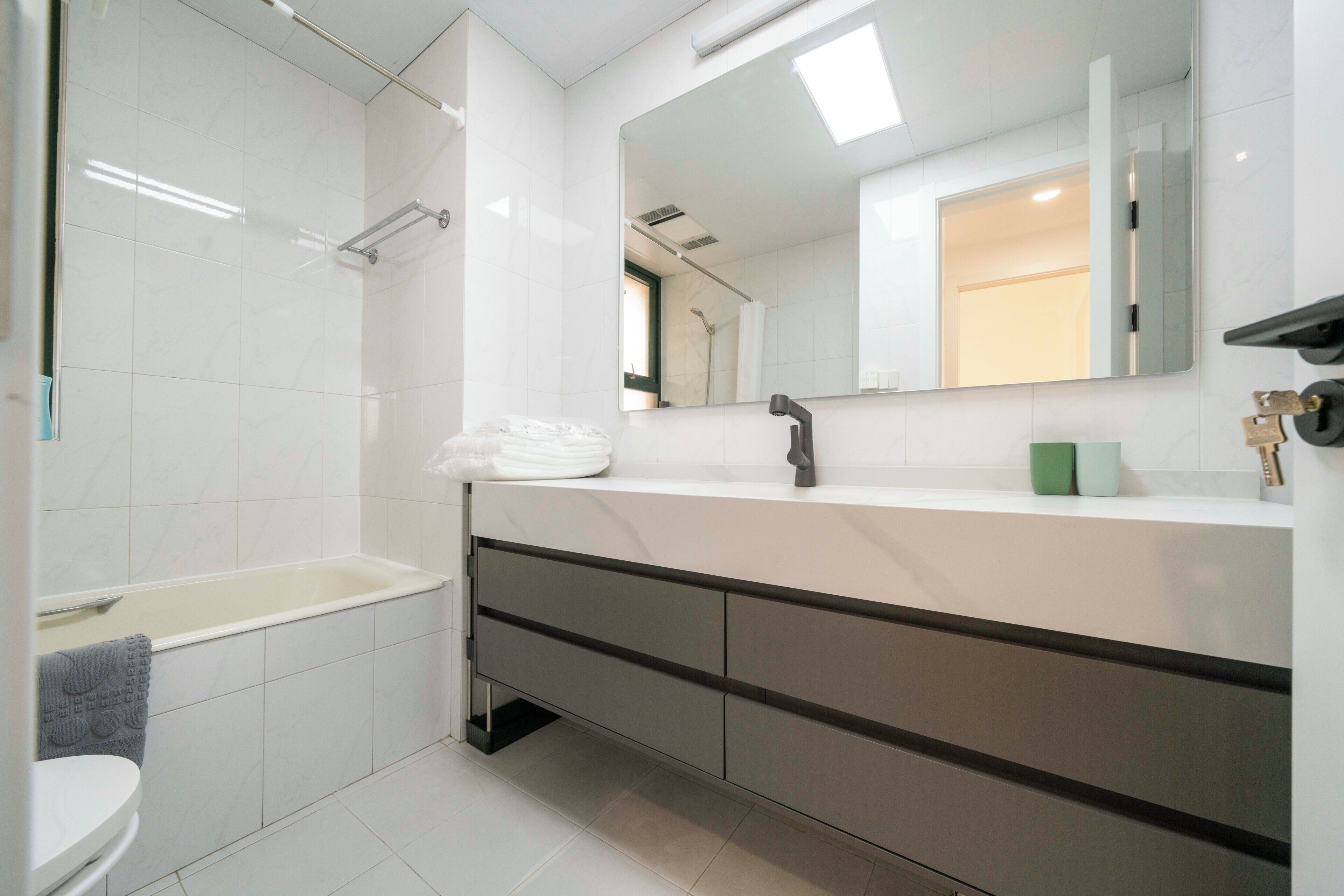 A modern bathroom with a bathtub, a toilet, a vanity with a mirror, and a shower area.