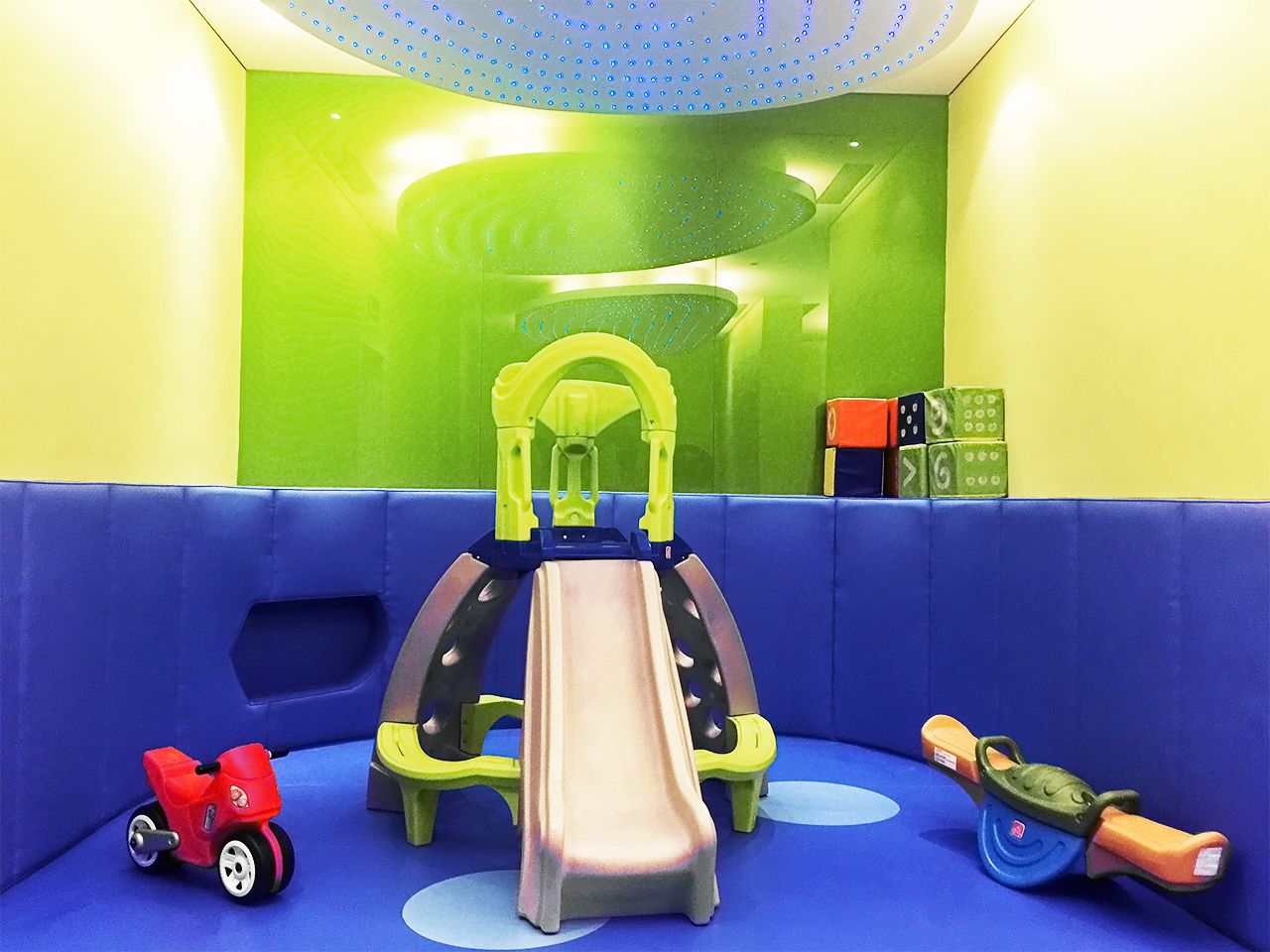A children's play area with a slide, a small red toy car, and a green toy boat.