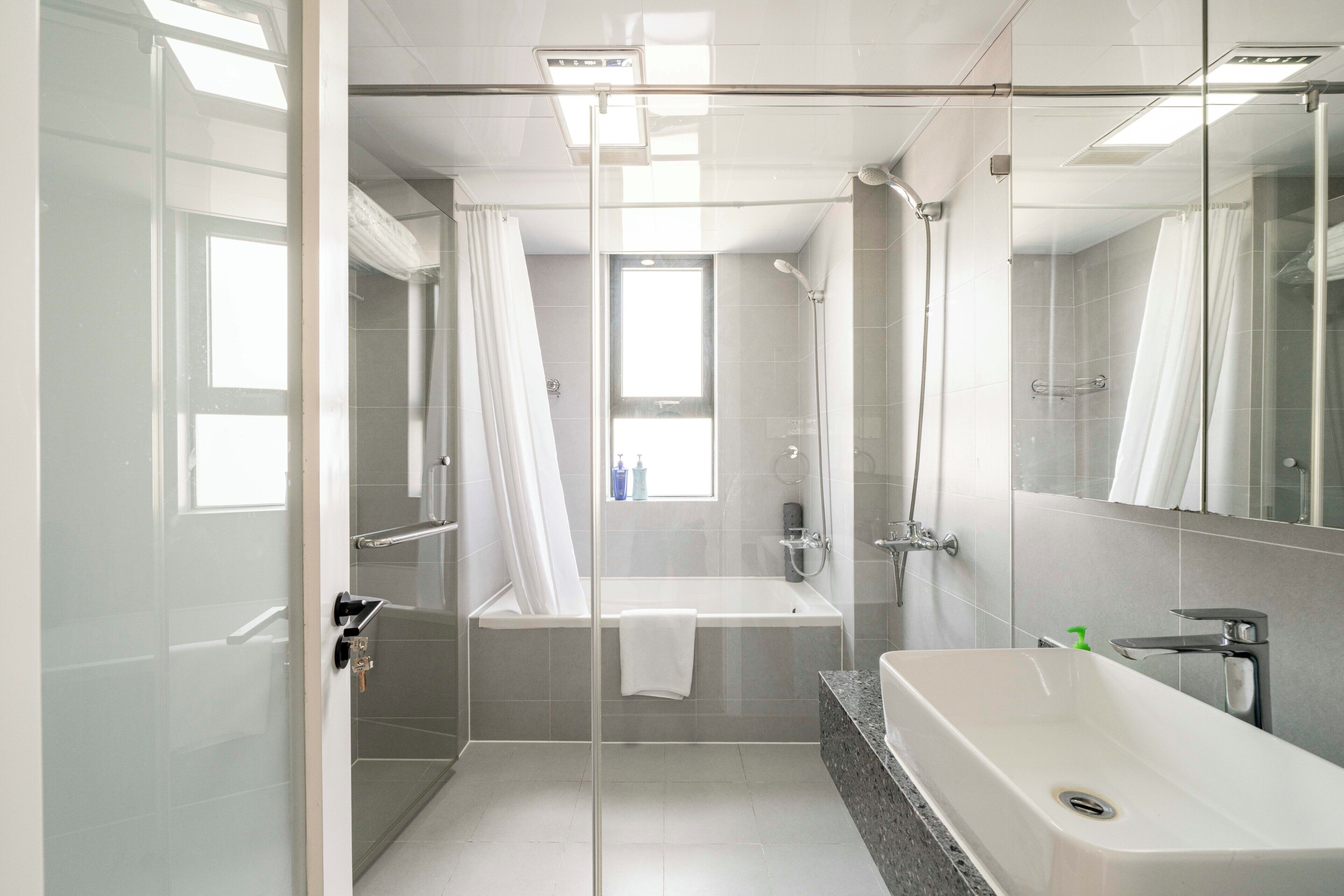 A modern bathroom with a glass shower enclosure, a bathtub, and a separate sink area.
