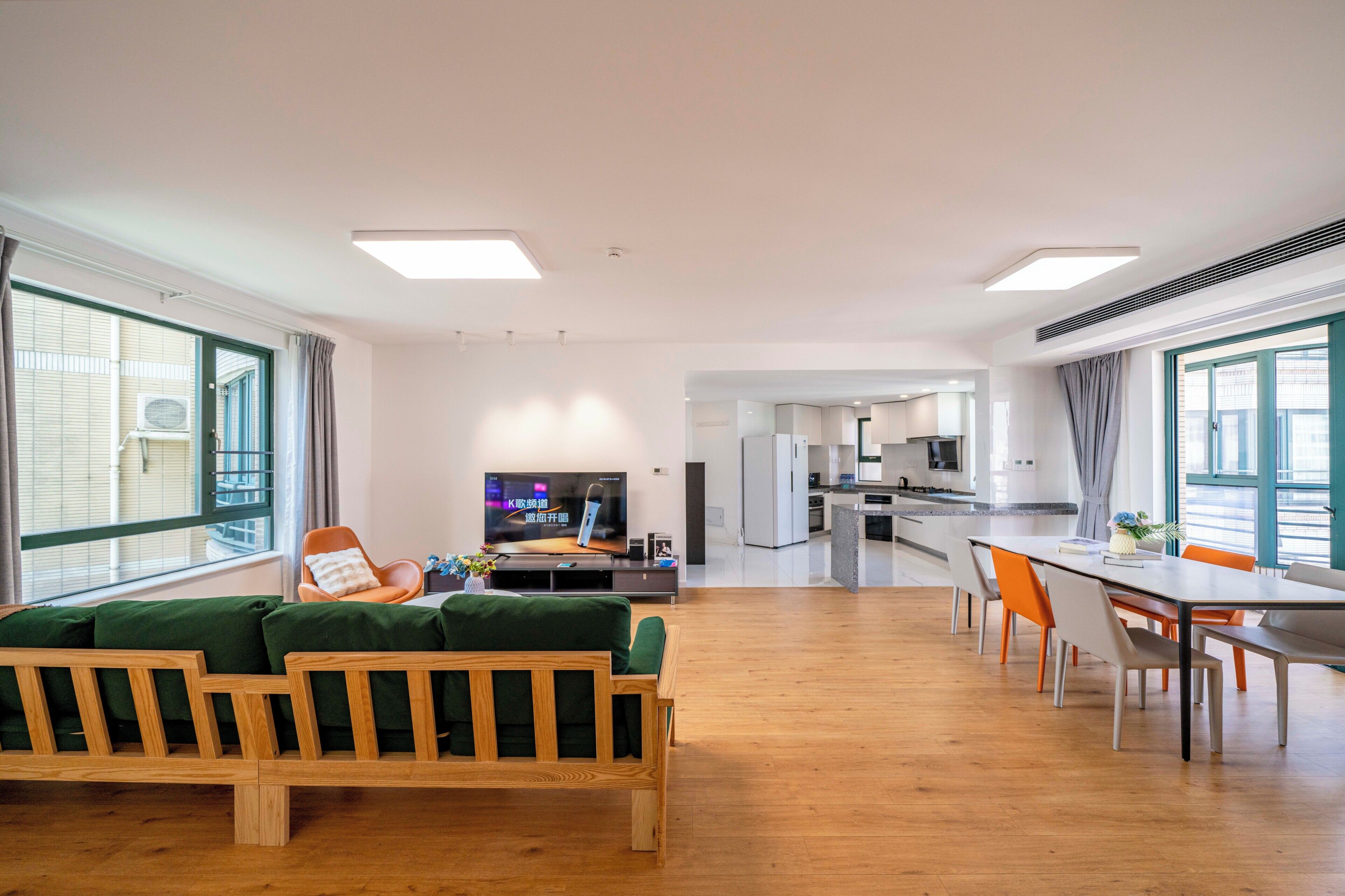 Un salon moderne avec un canapé, une table à manger et des chaises, et une cuisine en arrière-plan.