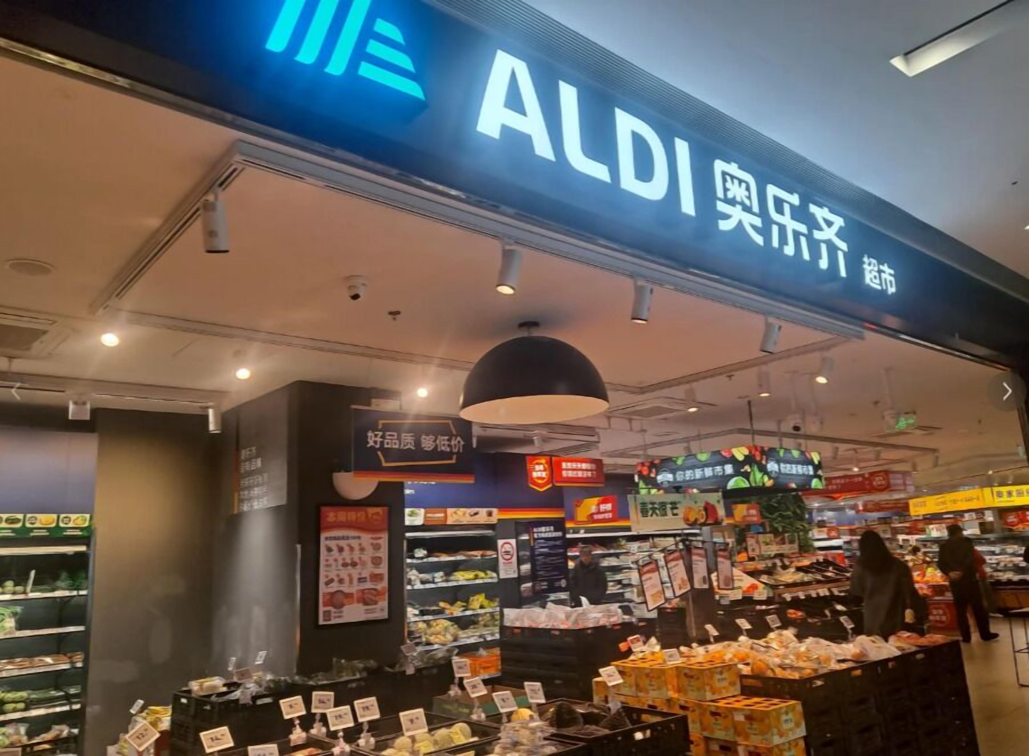 The exterior of an ALDI supermarket with a variety of products on display and signage in multiple languages.