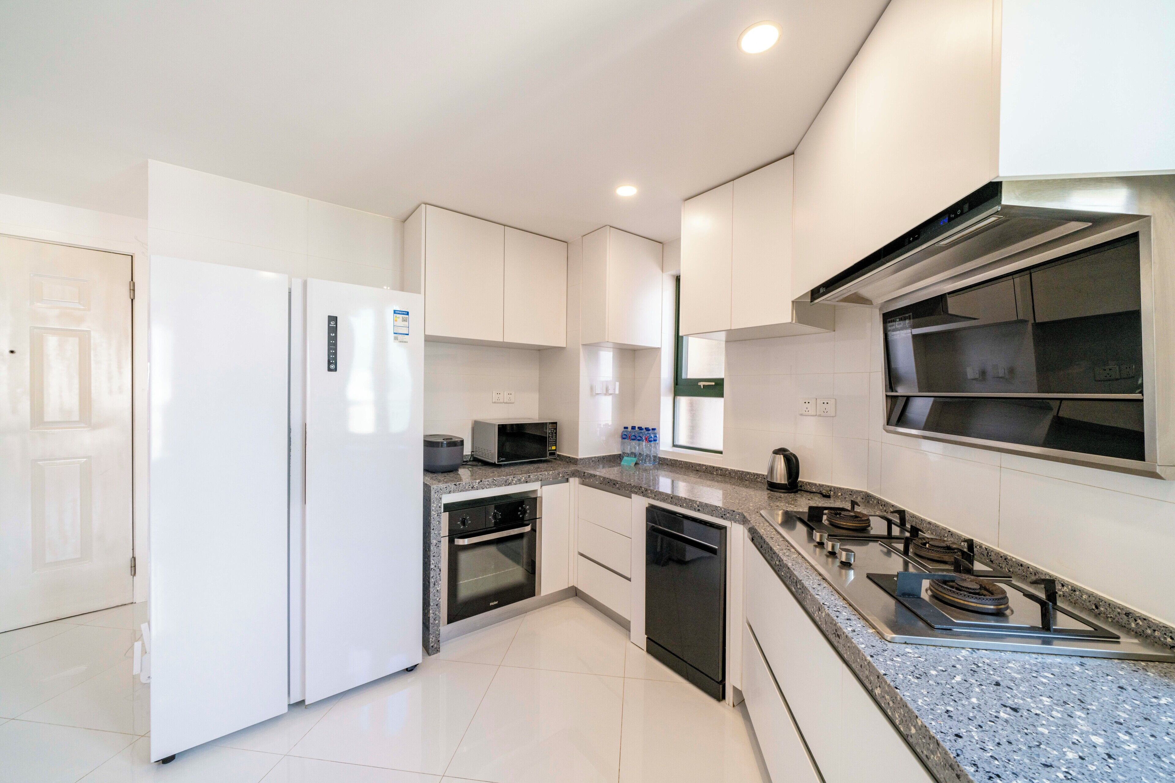 A modern kitchen with white cabinets, a built-in oven, a microwave, and a gas stove.