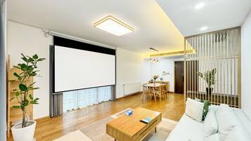 A modern living room with a sofa, coffee table, and a projector screen.
