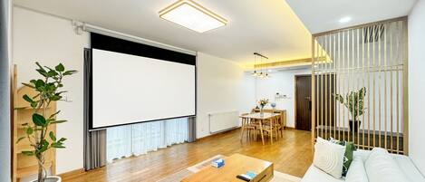 A modern living room with a sofa, coffee table, and a projector screen.