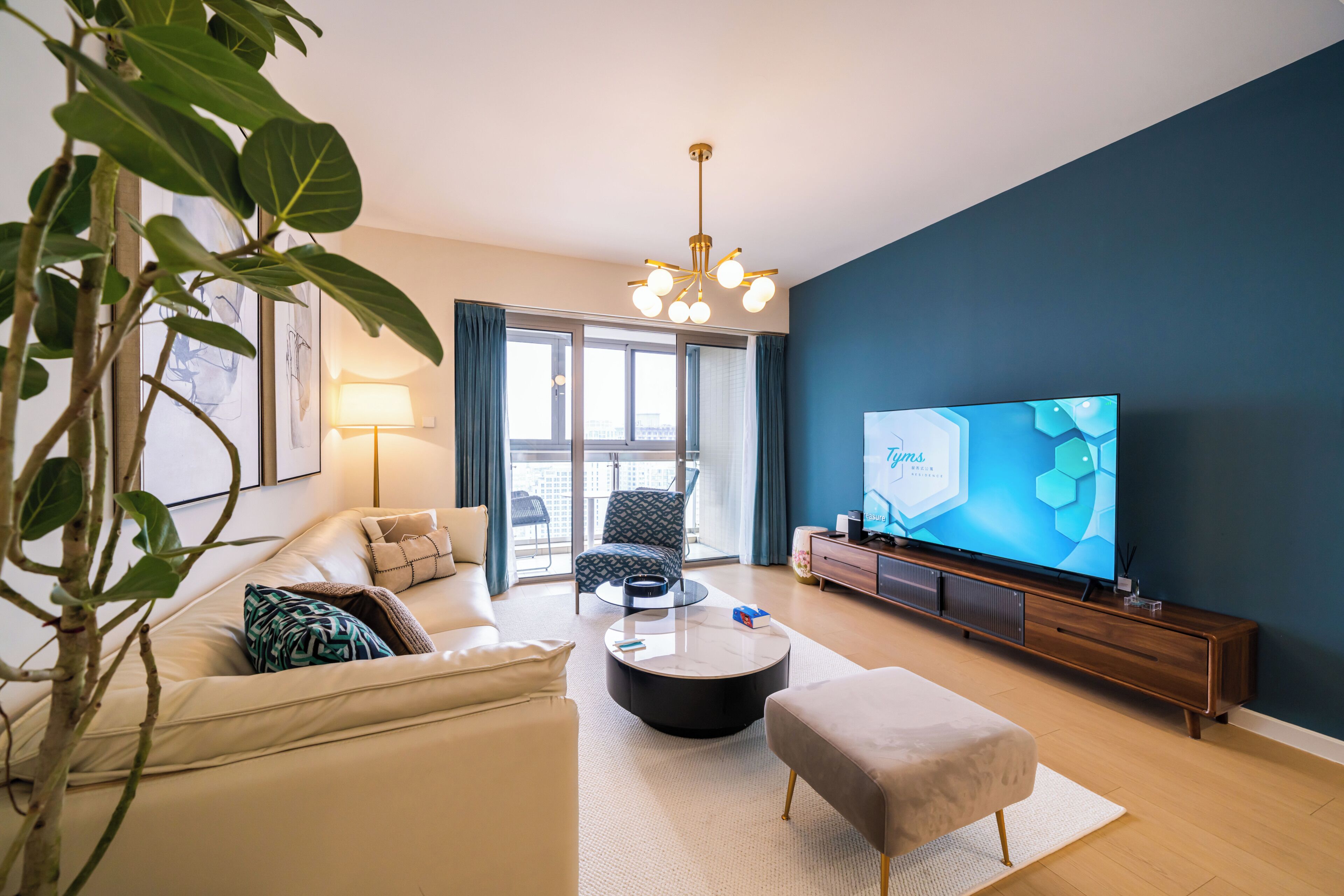 Un salon moderne avec un canapé, un pouf, une table basse et un téléviseur posé sur un meuble en bois.