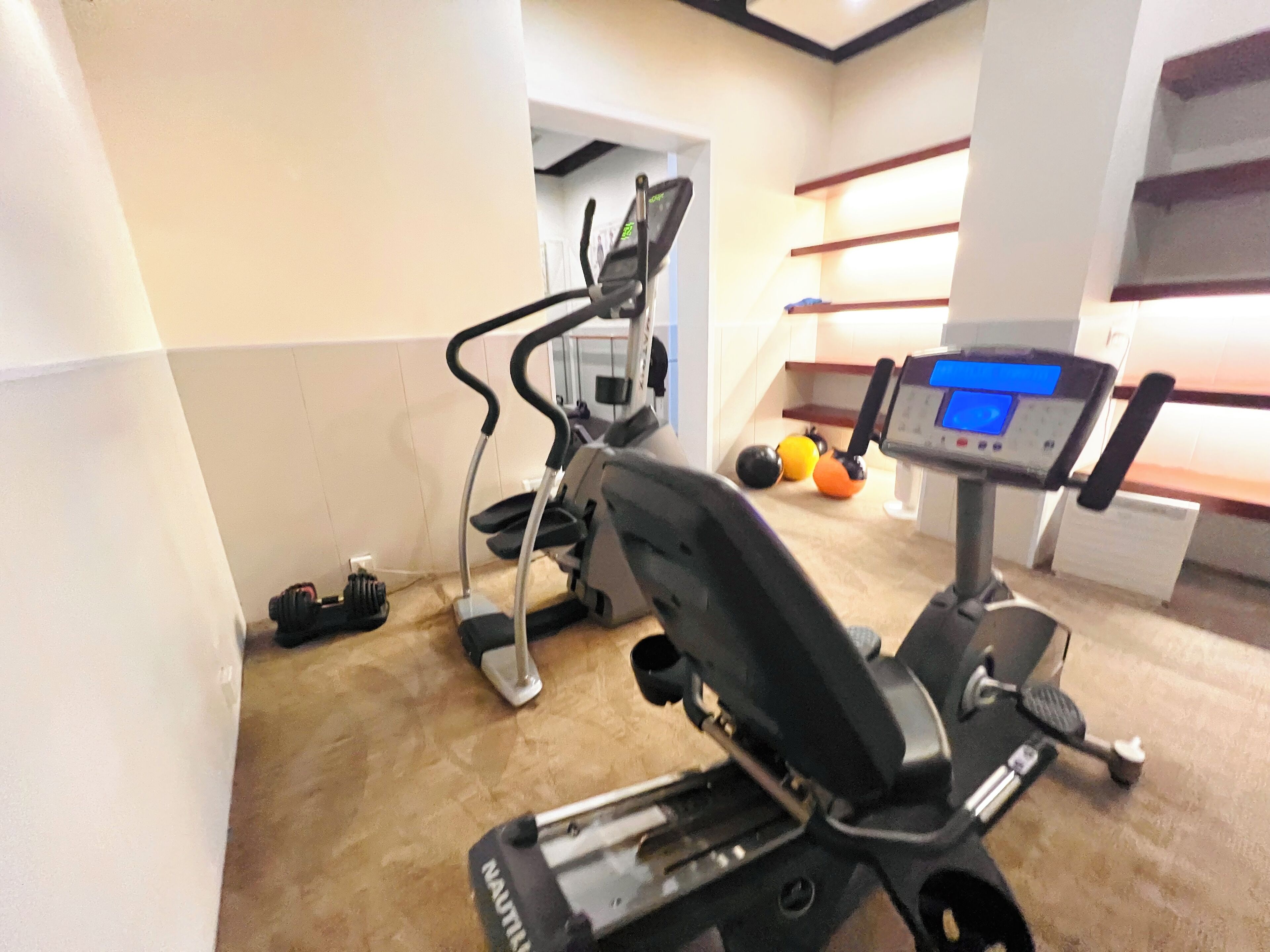 Un gimnasio con cintas de correr, una bicicleta estática y una máquina de remo.