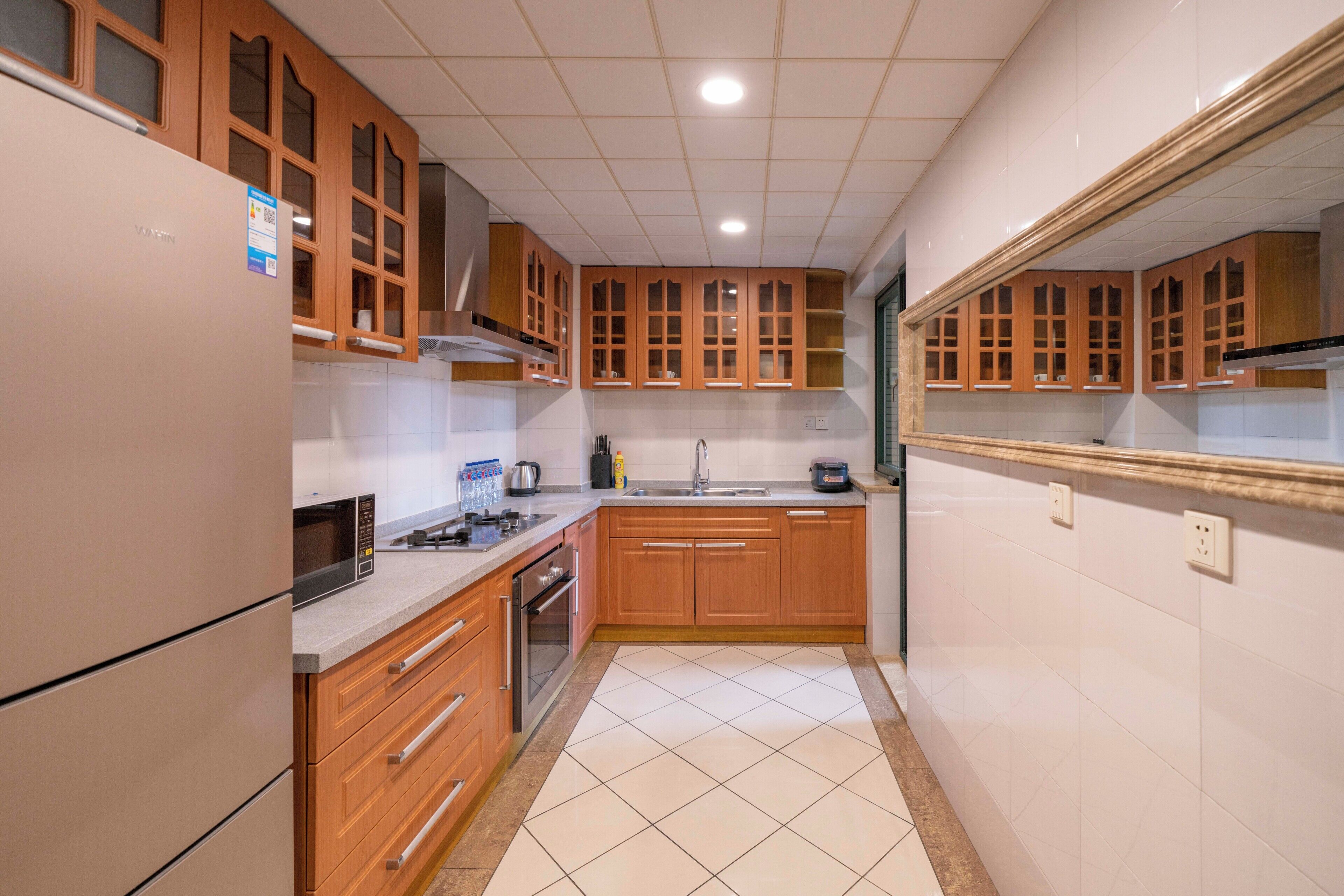 Une cuisine avec des meubles de rangement en bois, un four à micro-ondes, un évier et une cuisinière.
