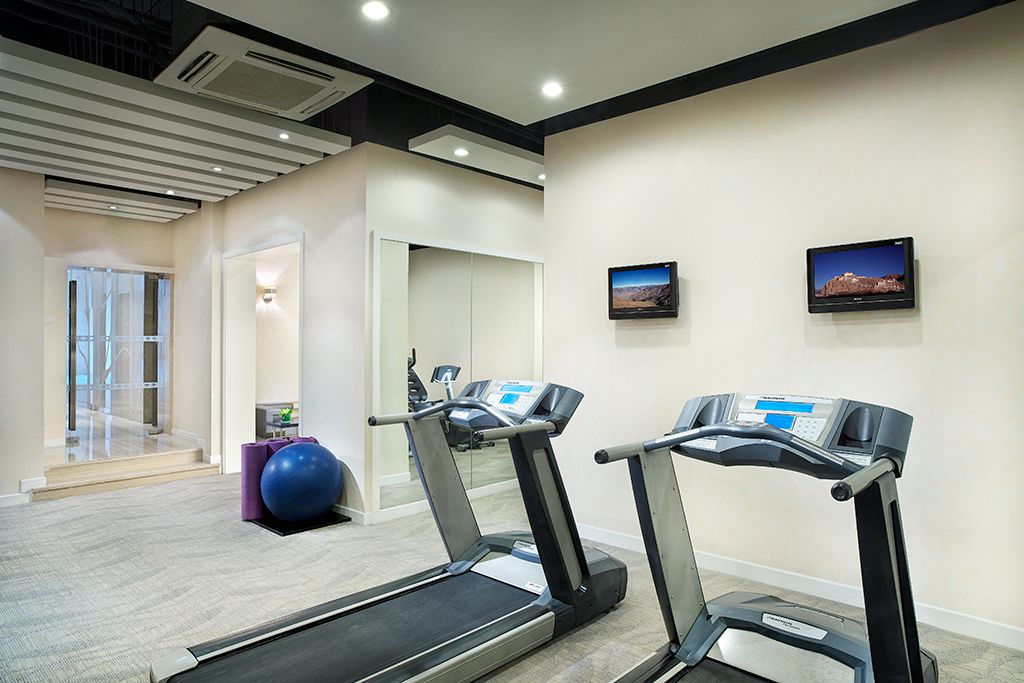 A modern gym with treadmills, a stationary bike, and a blue exercise ball.