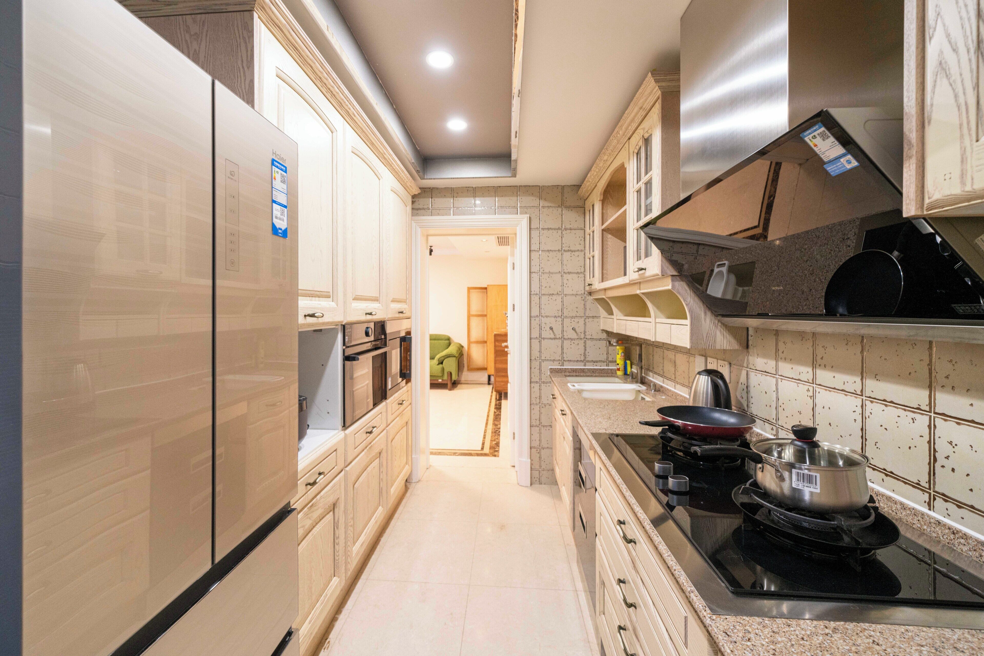 A kitchen with a refrigerator, stove, and cabinets.