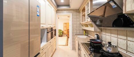A kitchen with a refrigerator, stove, and cabinets.