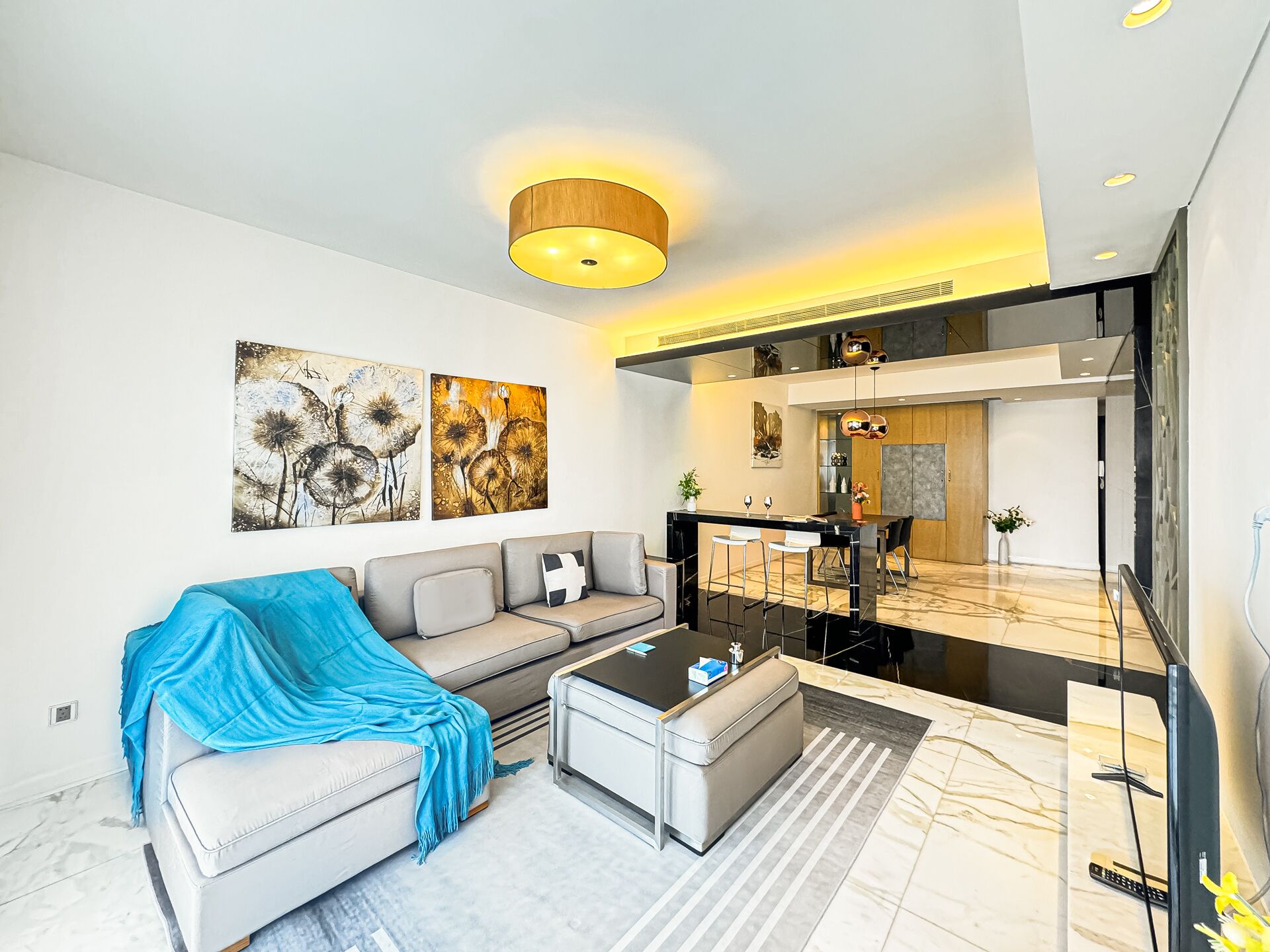 A modern living room with a sofa, coffee table, and artwork on the wall.