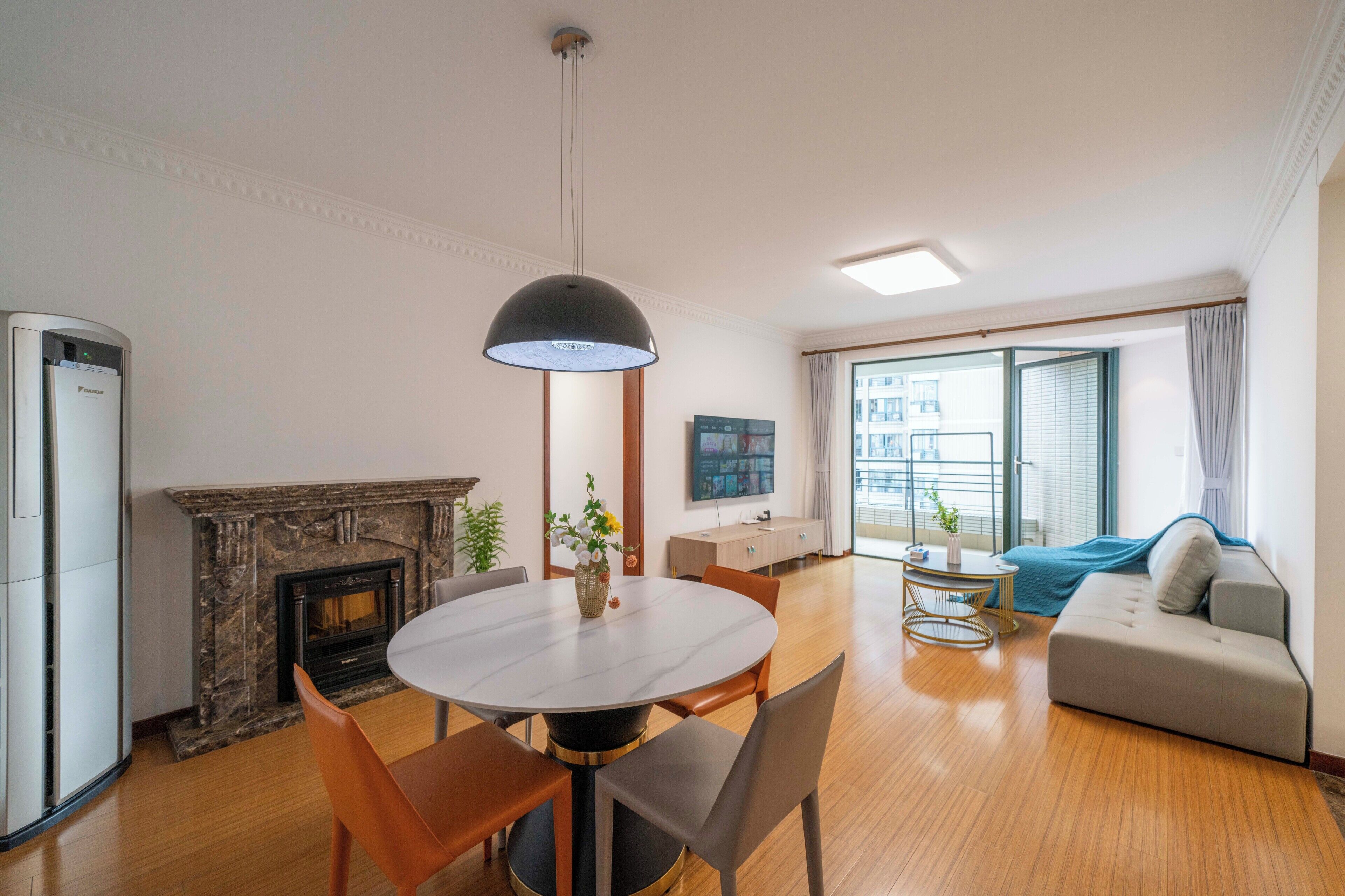 A modern living room with a fireplace, a round dining table, and a sofa.