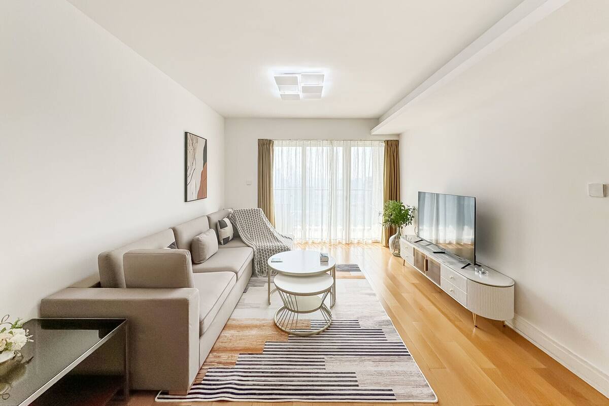 A modern living room with a sofa, a round coffee table, a TV, and a plant.