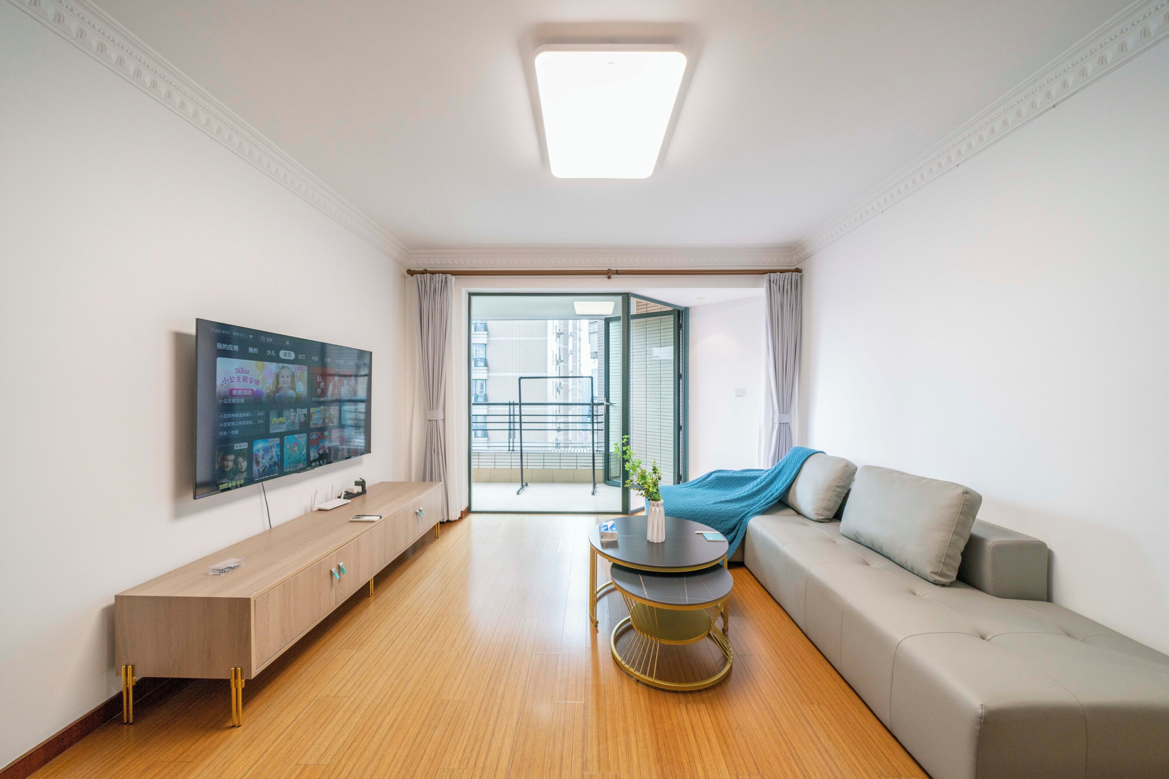 A modern living room with a flat-screen TV, a sofa, a coffee table, and a wooden cabinet.