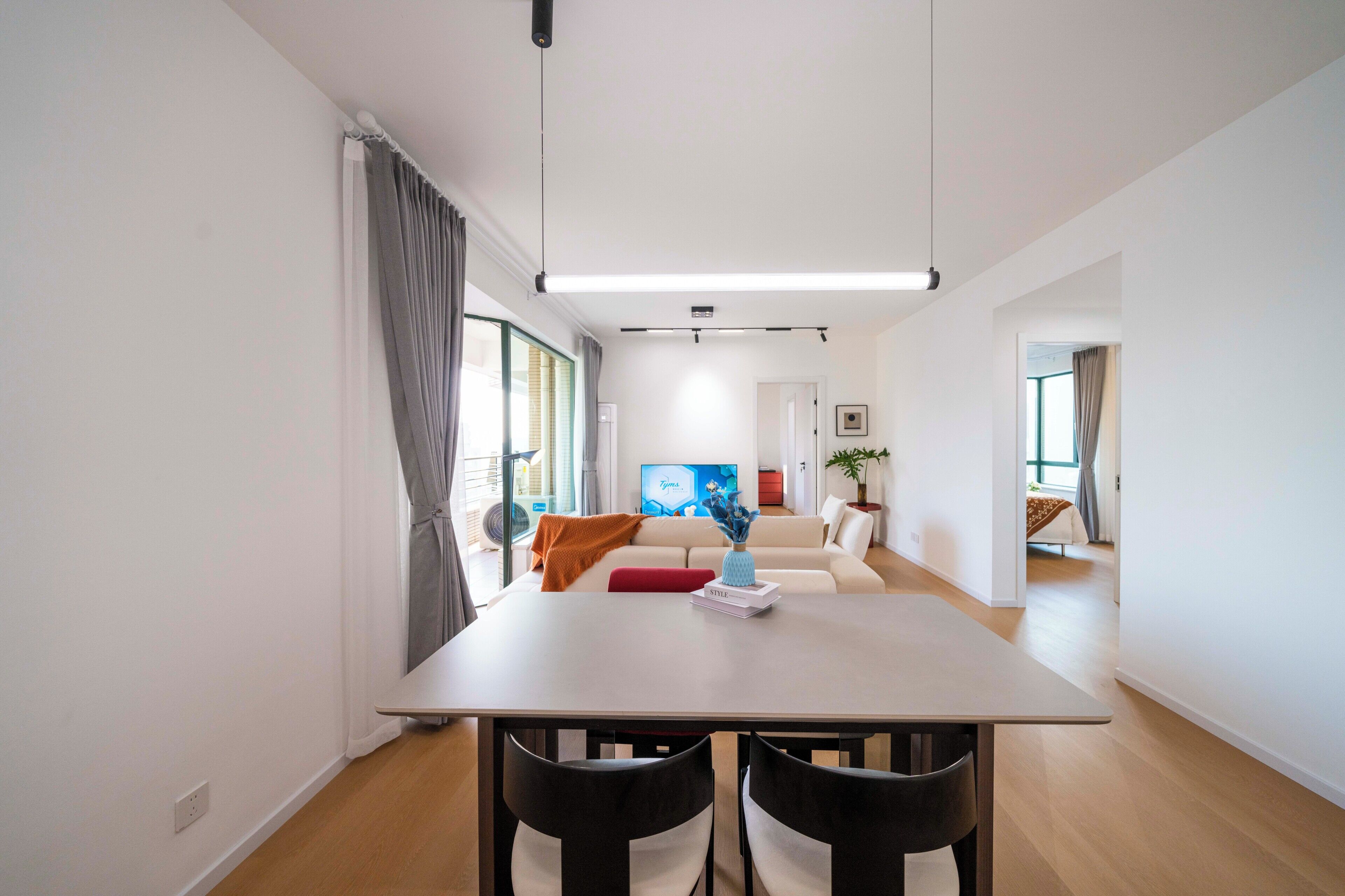 A modern living room with a sofa, a dining table with chairs, and a TV.