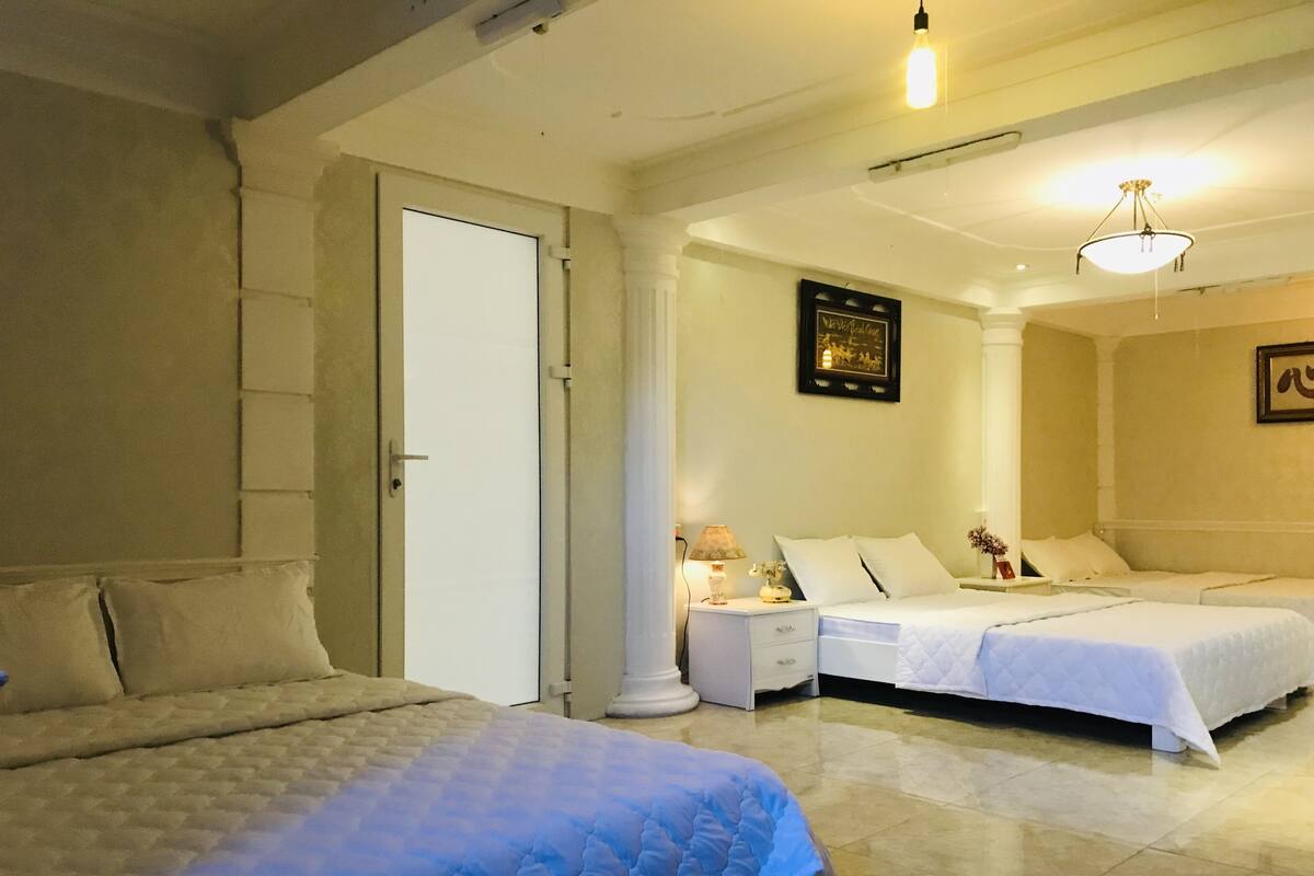 A hotel room with two beds, a nightstand, a lamp, and a framed picture on the wall.