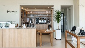 Una cafetería con mostrador de madera, una máquina de café y una pizarra con el menú.