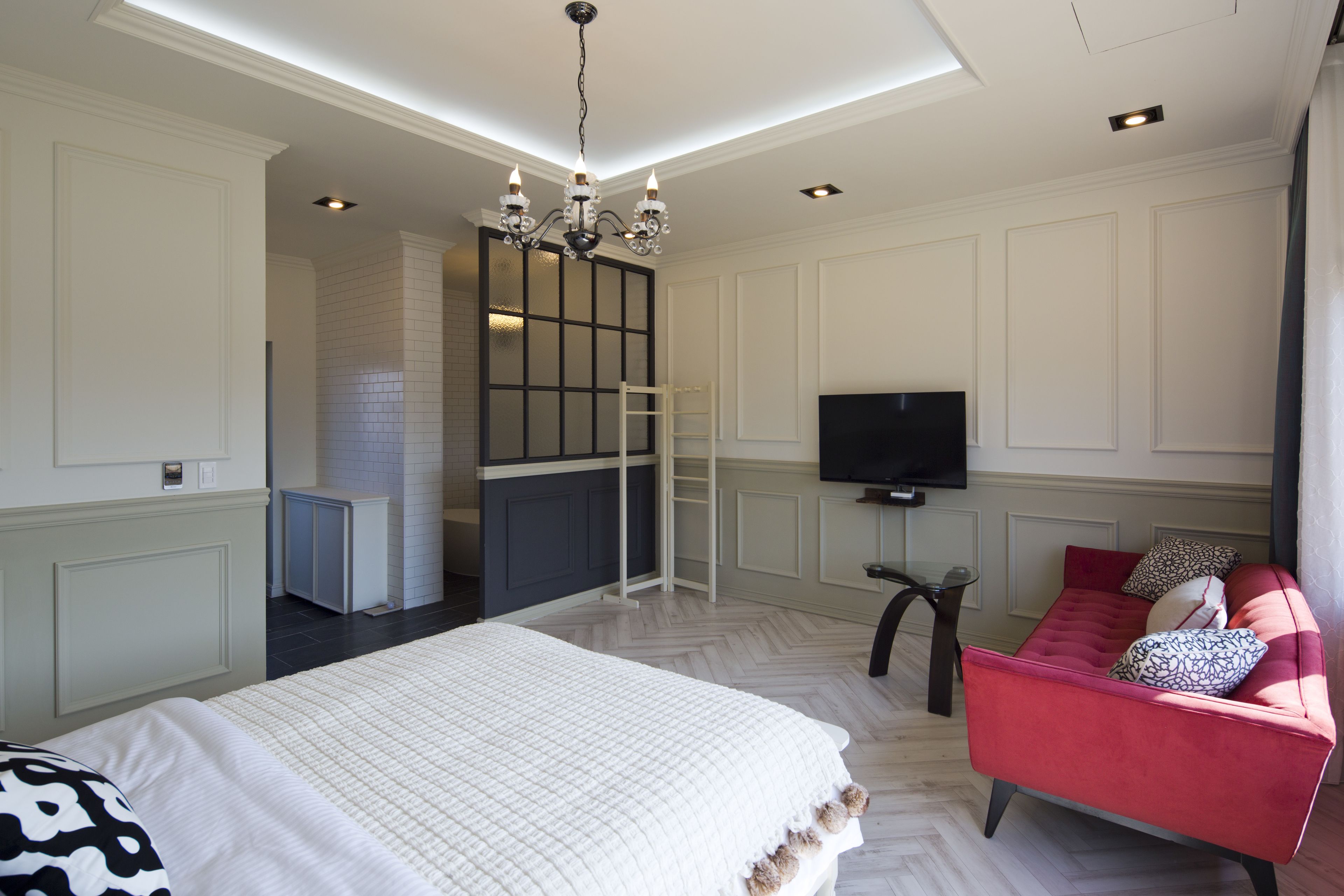 A bedroom with a bed, a TV, a red sofa, and a ladder.