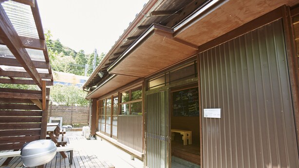 A wooden building with a covered patio area, a bicycle, and a small table. - Preta Torami - Hostel (Ichinomiya)