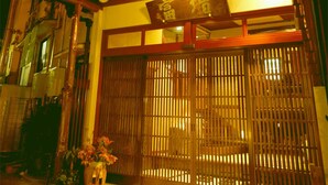 Un edificio japonés tradicional con estructura de madera, un letrero con caracteres japoneses y una verja de madera.