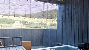 Una terraza de madera con un jacuzzi y una silla de mimbre.