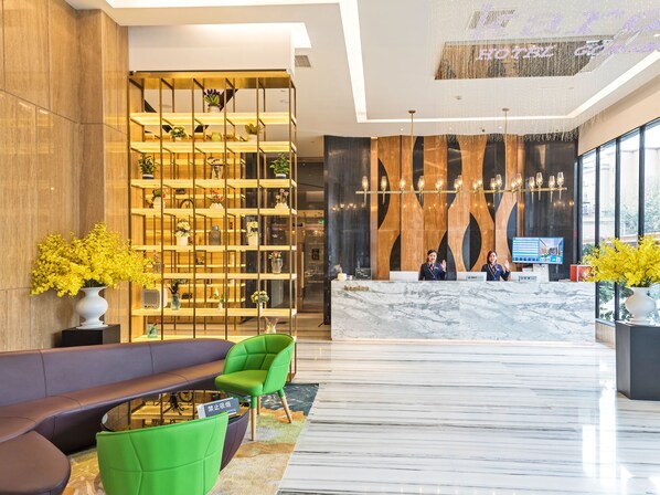 A modern hotel lobby with a reception desk, seating area, and a decorative plant display. - Guangzhou Kardon Hotel Gorgeous (Guangzhou)