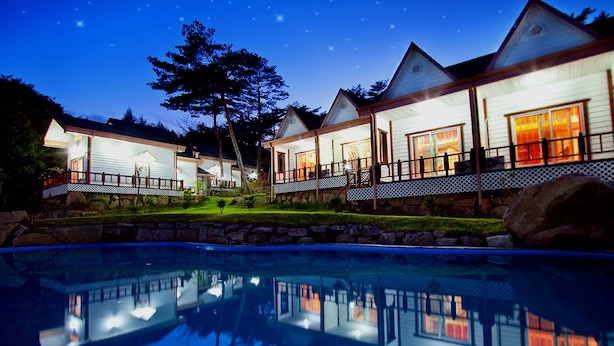 Un resort con varias cabañas para huéspedes, una piscina y un muro de contención de piedra.