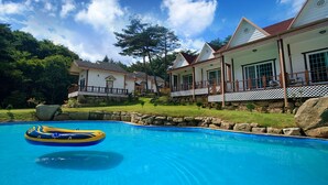 Una piscina con una balsa, rodeada por un muro de piedra y una terraza de madera.