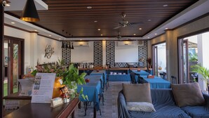 A restaurant with multiple tables and chairs, a counter with a menu, and a sofa area.